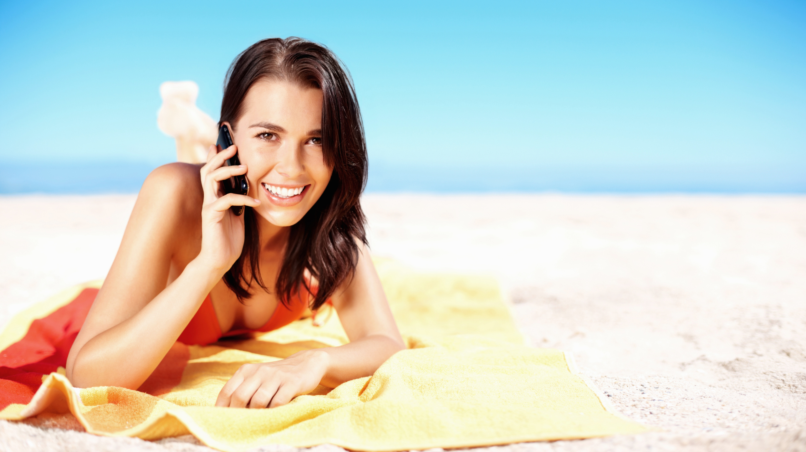 Sensuous young girl over the cell phone on beach, copyspace